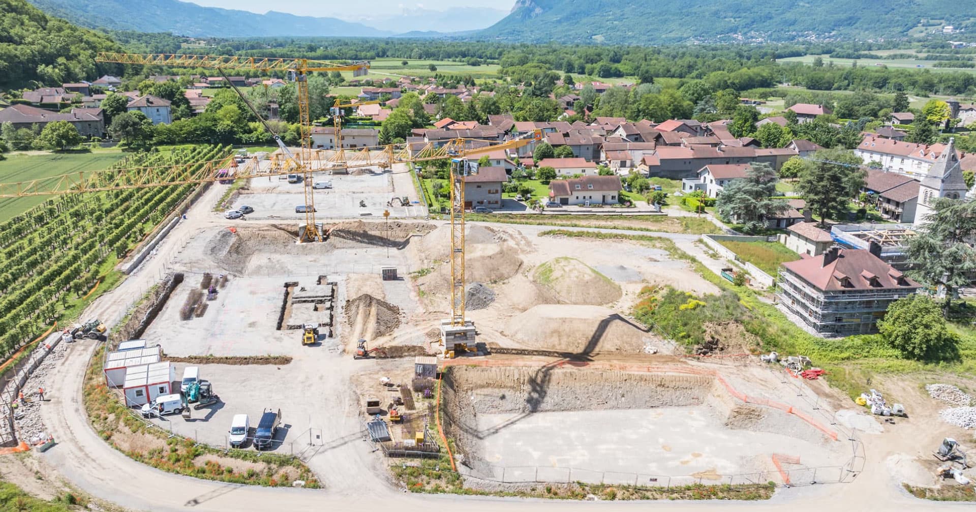 134-Actu_Cheylas_travaux Vu de drône du chantier de construction de la résidence Beauvillahe au Cheylas en Isère avec les grues et les engins de chantier.